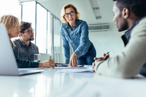 Group of people huddled around a table reading and talking about a document 