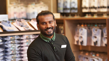 Picture of someone smiling with packaged shirts in the background