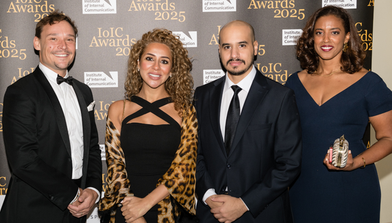 Four guests pose at the IoIC Awards 2025 backdrop, one holding a trophy.